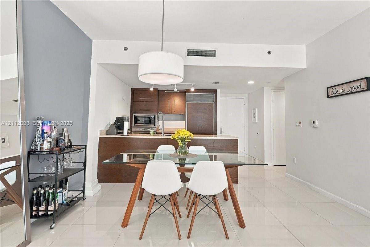 Kitchen featuring dark wood-finish cabinetry, solid-surface countertops, built-in stainless steel appliances, and tile flooring