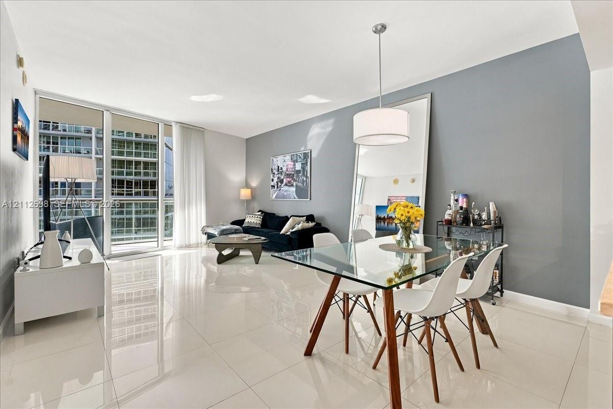Open-concept interior featuring polished porcelain tile flooring, expansive floor-to-ceiling windows, and a dedicated drum pendant light fixture