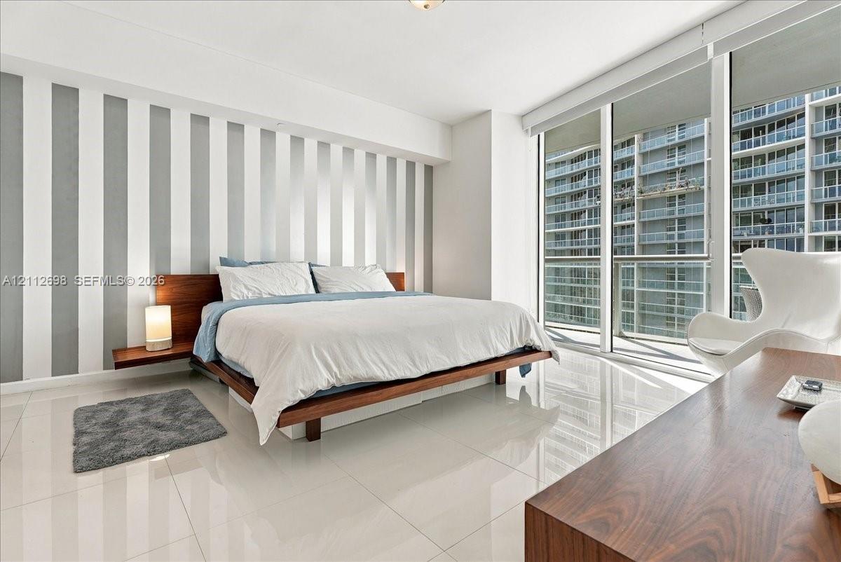 Floor-to-ceiling windows, polished tile flooring, and integrated wall-mounted bedside shelving