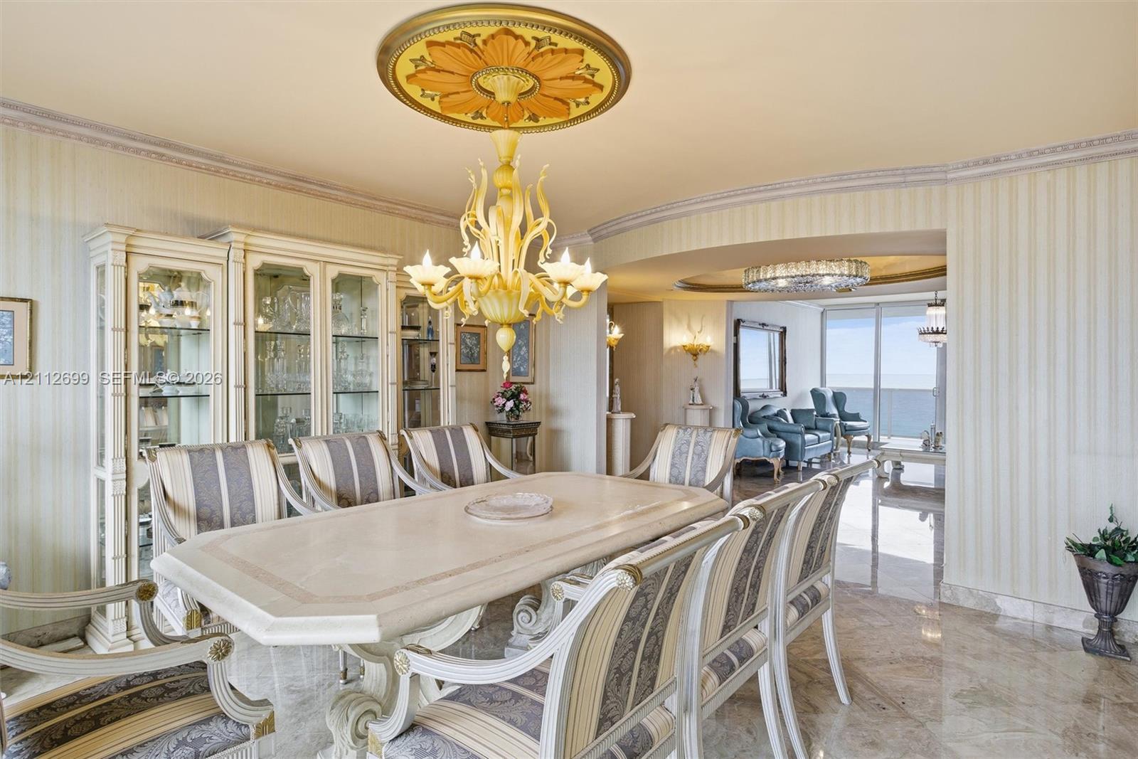 Formal dining area featuring stone flooring, integrated built-in cabinetry, an ornate decorative ceiling medallion, and a multi-arm chandelier
