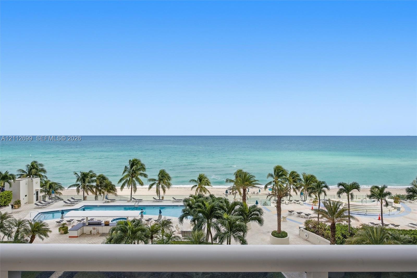Direct waterfront access with expansive ocean horizon, resort-style swimming pool, integrated poolside bar, and mature palm landscaping