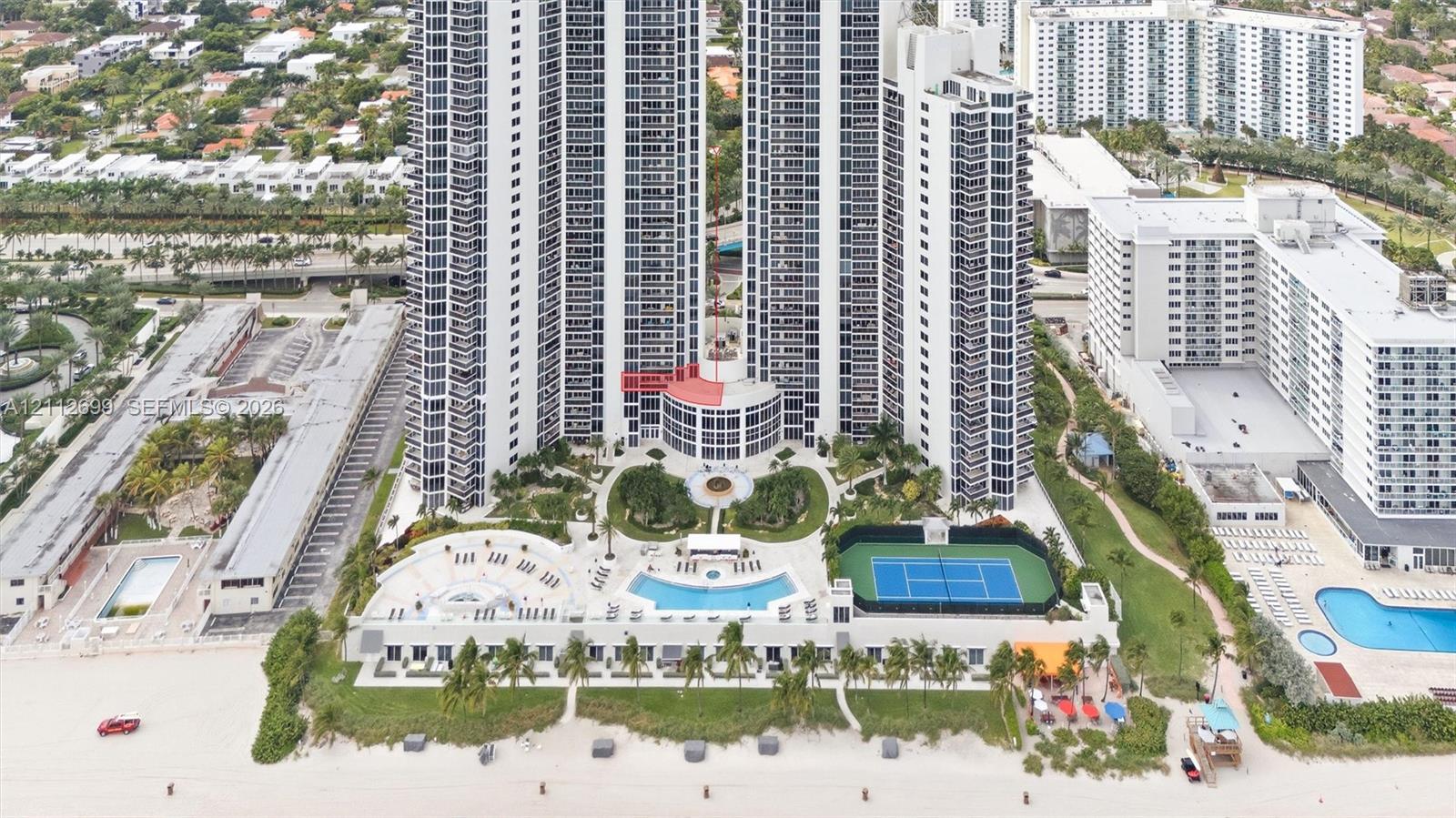 High-rise coastal property featuring an outdoor swimming pool, tennis court, landscaped grounds, and direct beach access