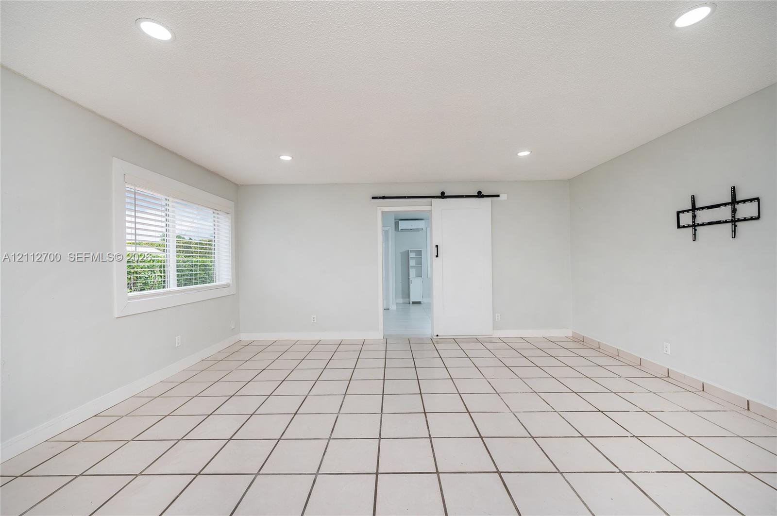 Interior space featuring ceramic tile flooring, recessed lighting, a sliding barn-style door, and a dual-pane window with white trim