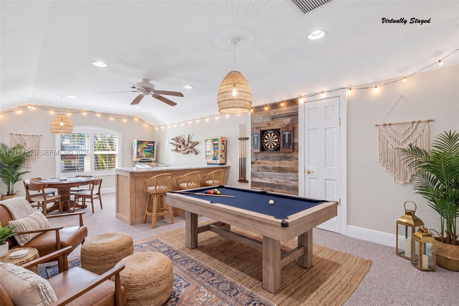 VIRTUALLY STAGED Vaulted ceilings with recessed lighting, integrated wet bar featuring light wood cabinetry, accent wall with reclaimed wood paneling, and ceiling fan fixture
