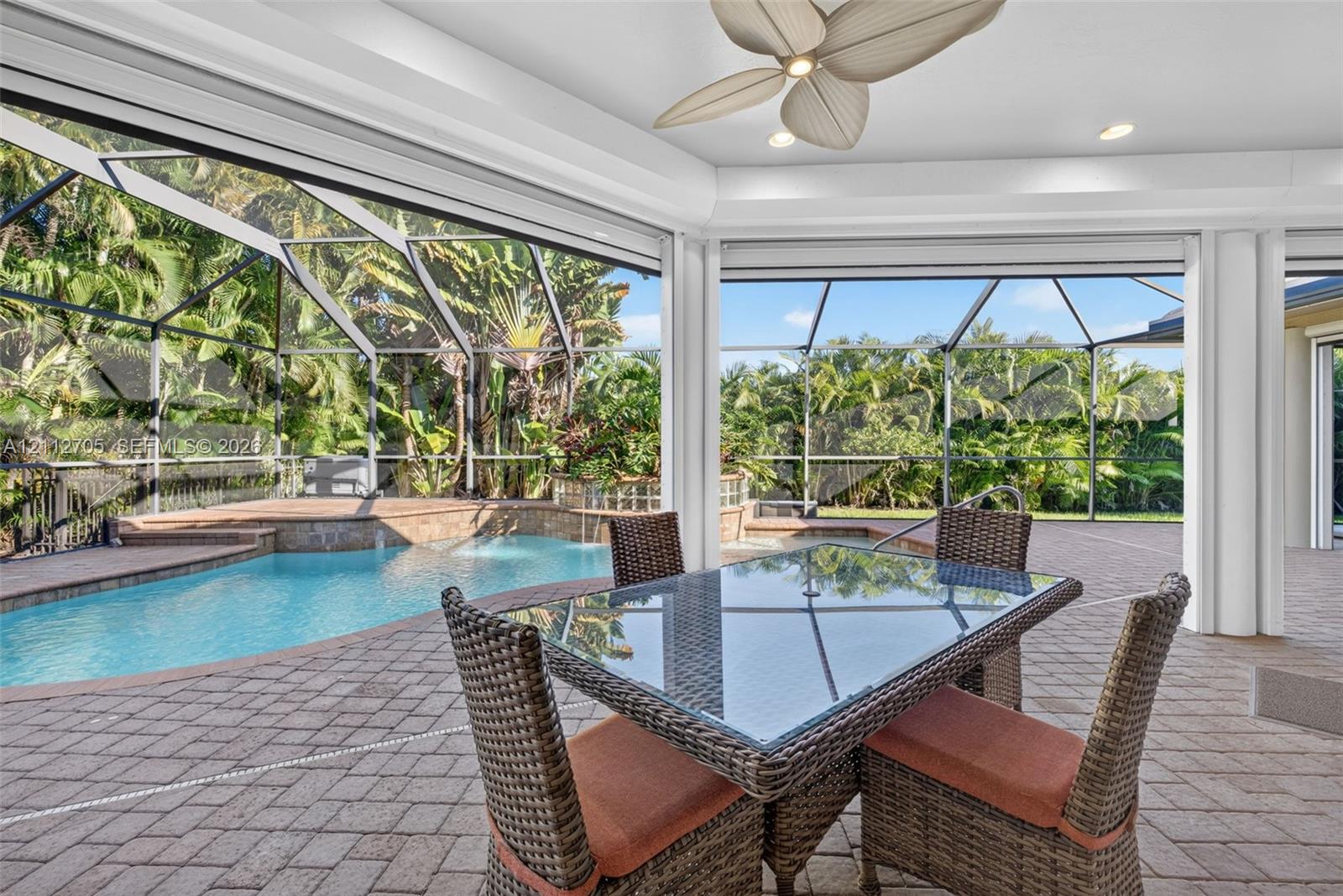 Screened-in lanai featuring a paver stone patio, a private swimming pool with integrated water feature, recessed lighting, and a ceiling fan