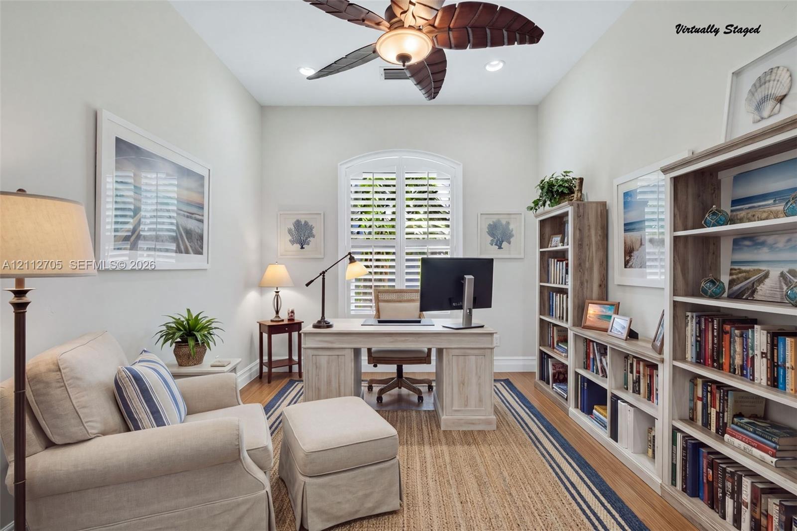 VIRTUALLY STAGED High ceilings, integrated palm-leaf blade ceiling fan, arched window with plantation shutters, and extensive built-in wood-finish shelving