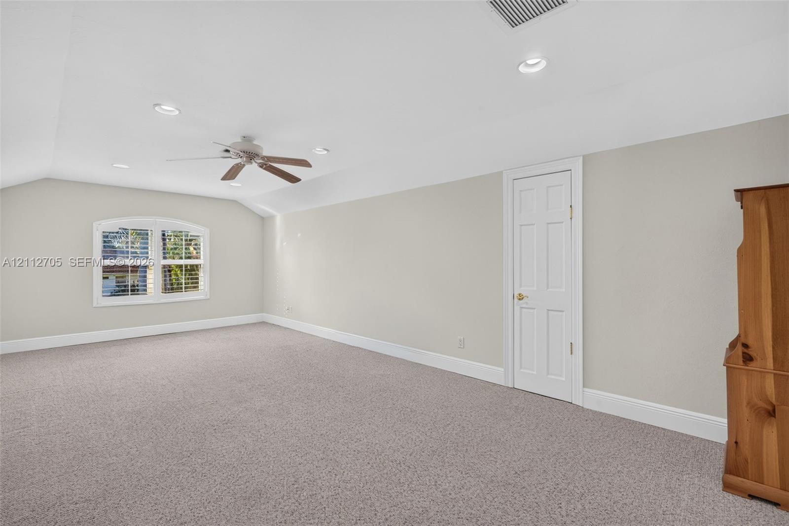 Room featuring vaulted ceilings, neutral carpeting, recessed lighting, a ceiling fan, and an arched window