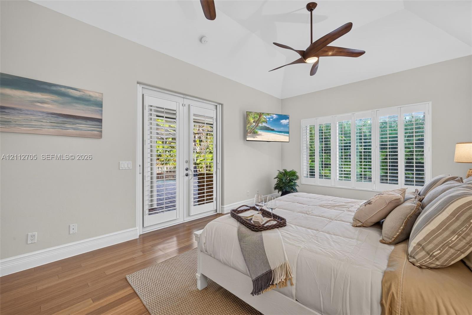 Vaulted ceilings, wood-finish flooring, plantation shutters, and glass-paned French doors