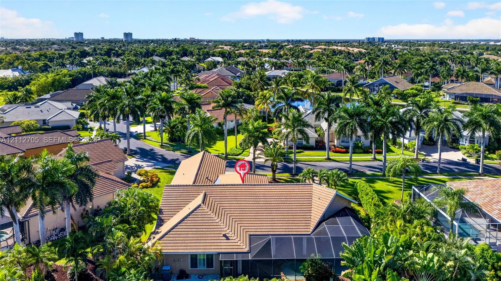 Aerial perspective featuring a tile roof, screened-in rear enclosure, and surrounding mature landscaping within a residential community