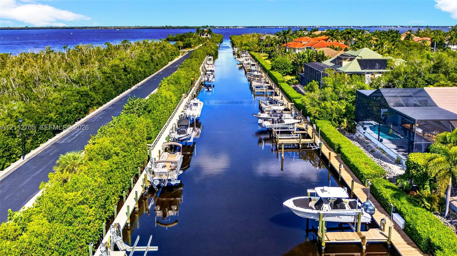 Waterfront property featuring a private boat dock, deep-water canal access, screen-enclosed pool, and coastal landscape
