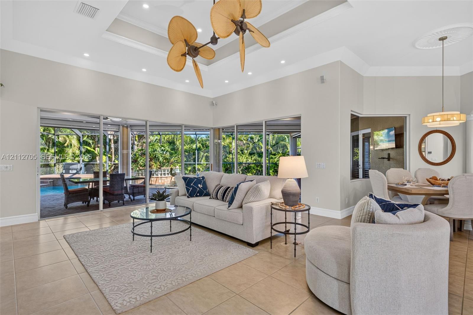 Tray ceiling with recessed lighting, multi-blade sculptural ceiling fan, large-format tile flooring, and expansive floor-to-ceiling glass sliding doors
