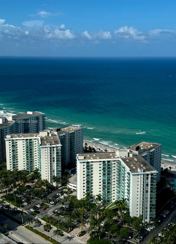 High-rise coastal towers featuring direct oceanfront exposure, balcony access, paved surface parking, and mature palm landscaping