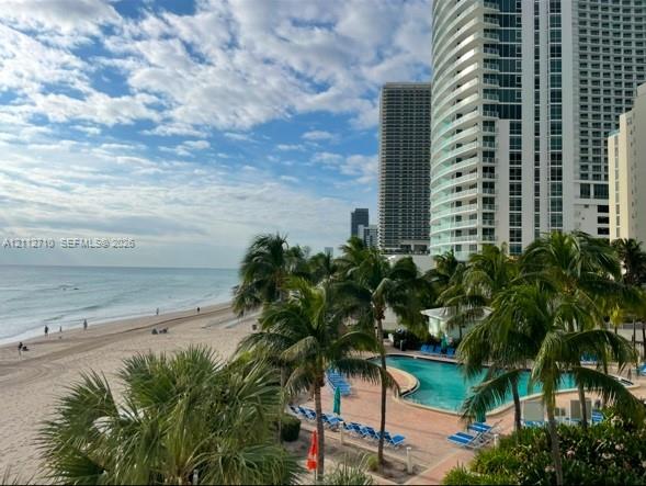 Oceanfront property featuring a swimming pool, stone-paver sun deck, and mature palm trees