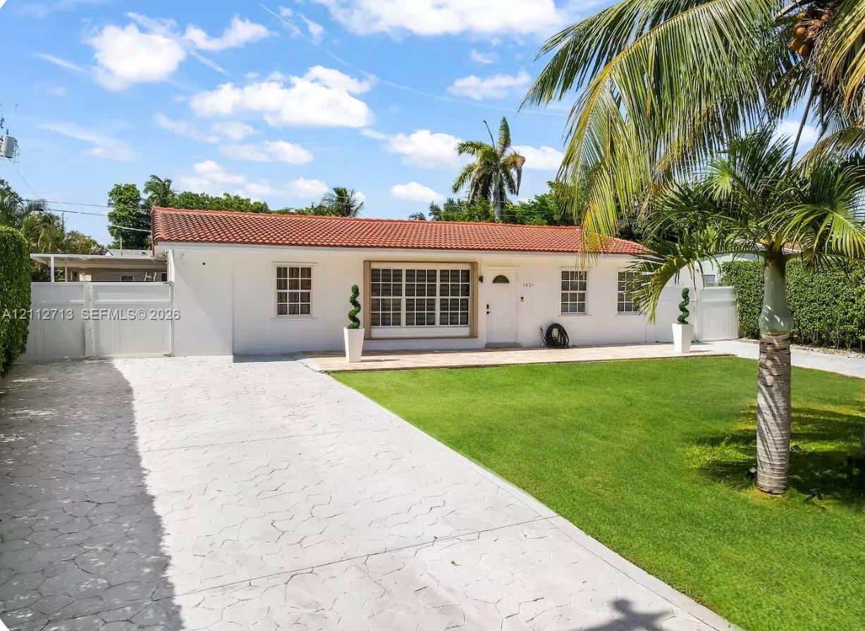Single-story exterior featuring a terracotta tile roof, white stucco facade, multi-lite grid windows, a stamped concrete driveway, and a manicured front lawn