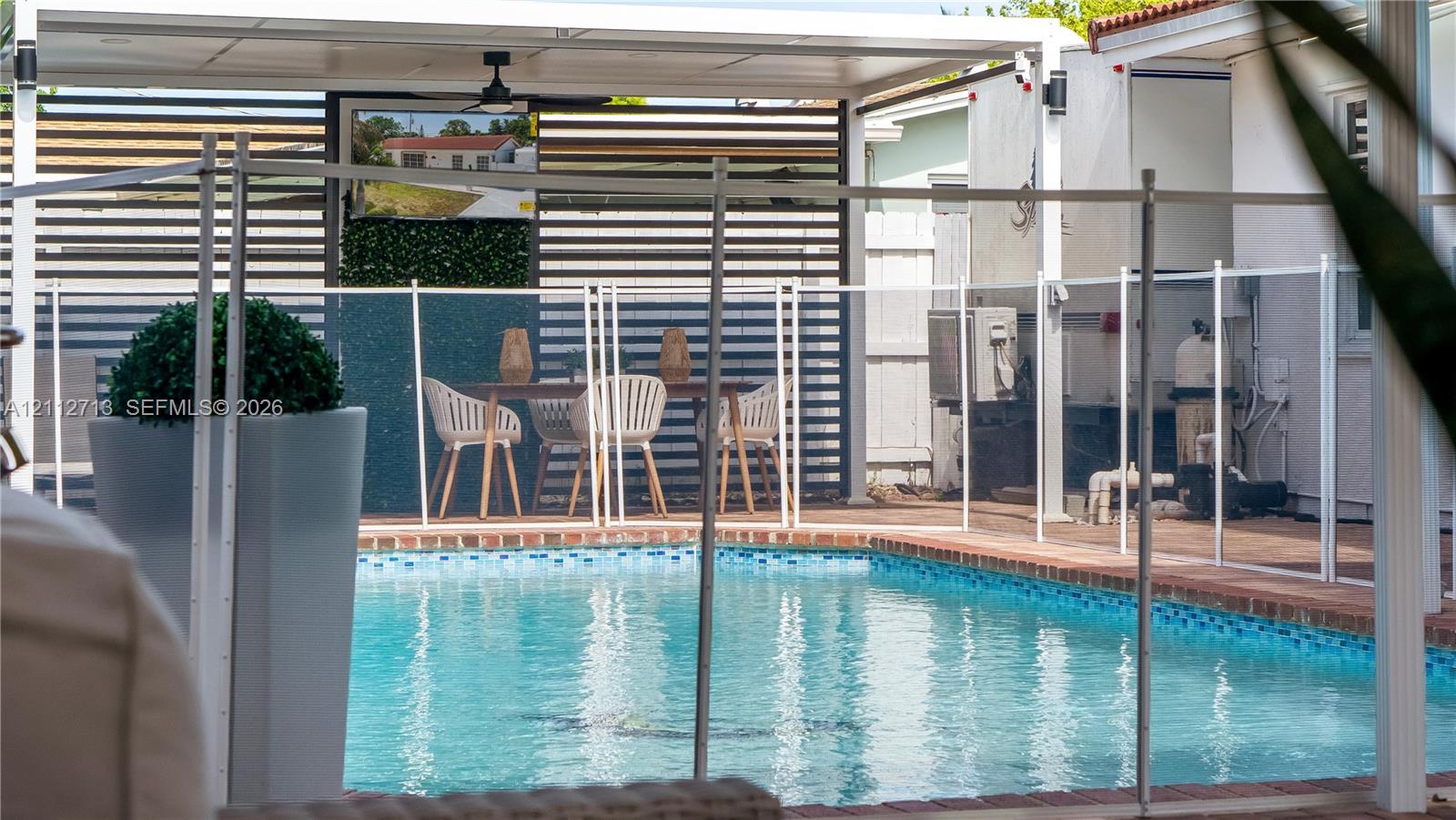 Backyard featuring an in-ground swimming pool, brick coping, and a covered patio area with horizontal privacy screening, a ceiling fan, and recessed lighting