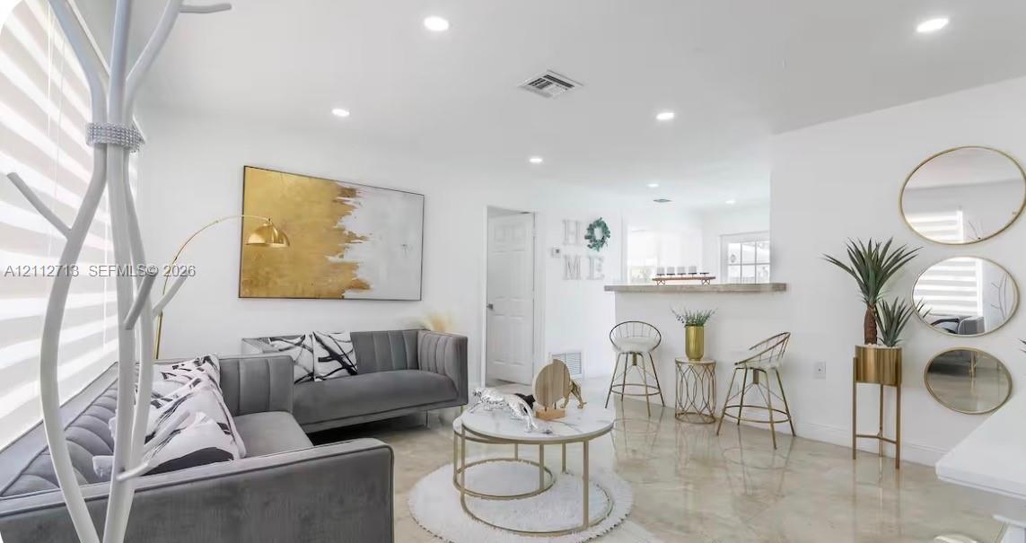 Living area featuring recessed lighting, polished tile flooring, and a breakfast bar with a stone-top counter