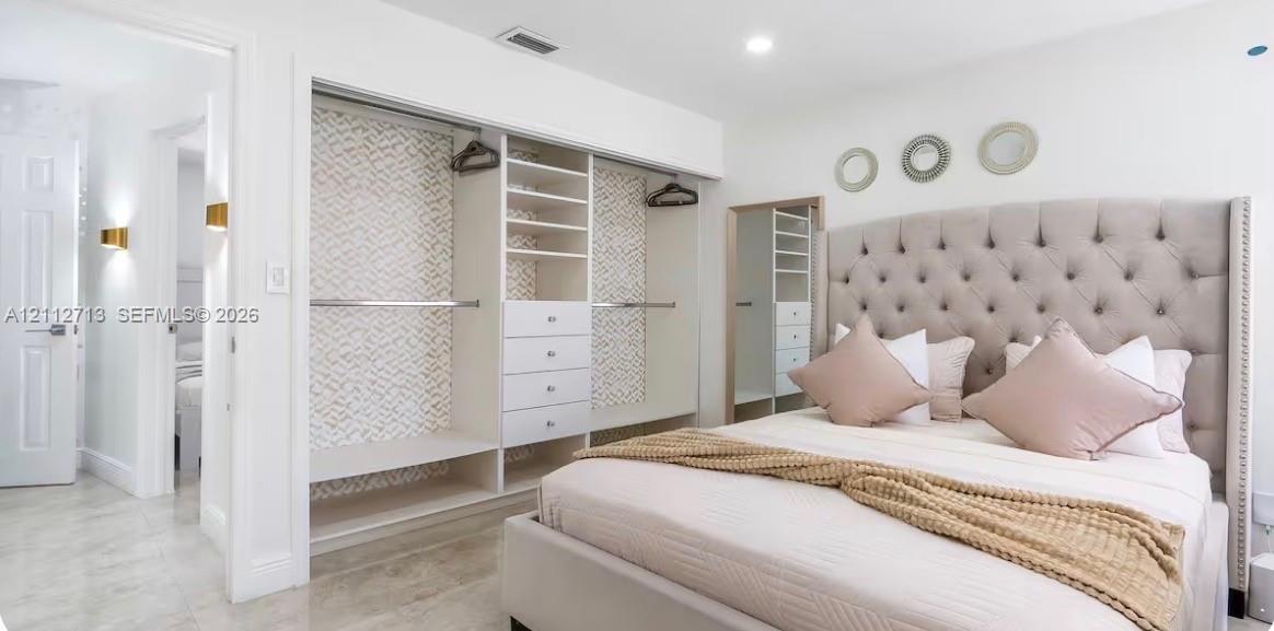 Custom built-in wardrobe featuring floor-to-ceiling shelving, integrated drawers, and dual hanging rods, illuminated by recessed lighting and wall-mounted sconces
