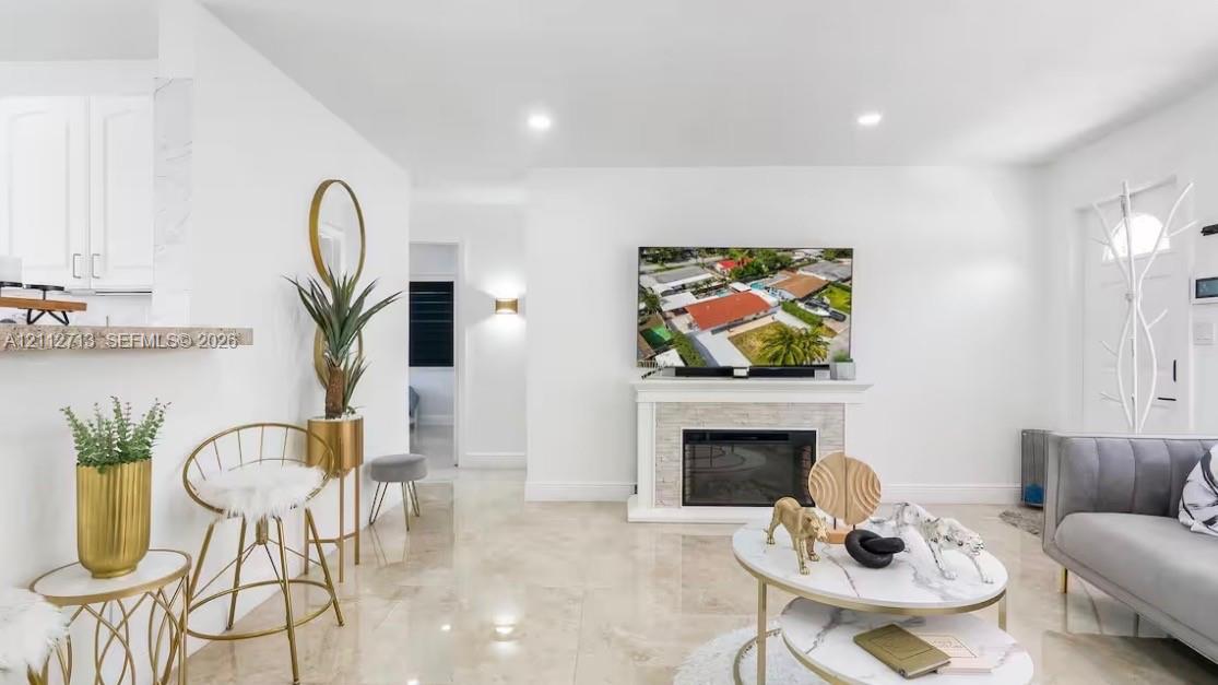 Living area featuring stone-finish flooring, a built-in fireplace with a textured surround, recessed lighting, and a breakfast bar with stone-finish counters