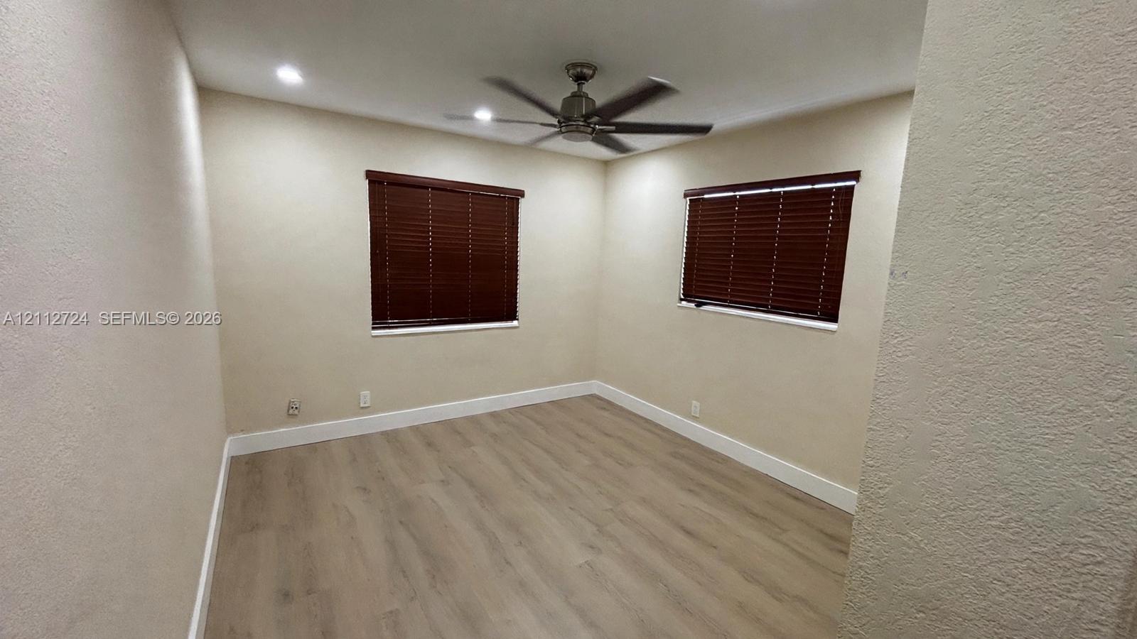 Interior space featuring wood-finish flooring, recessed lighting, a ceiling fan, and windows equipped with fitted blinds