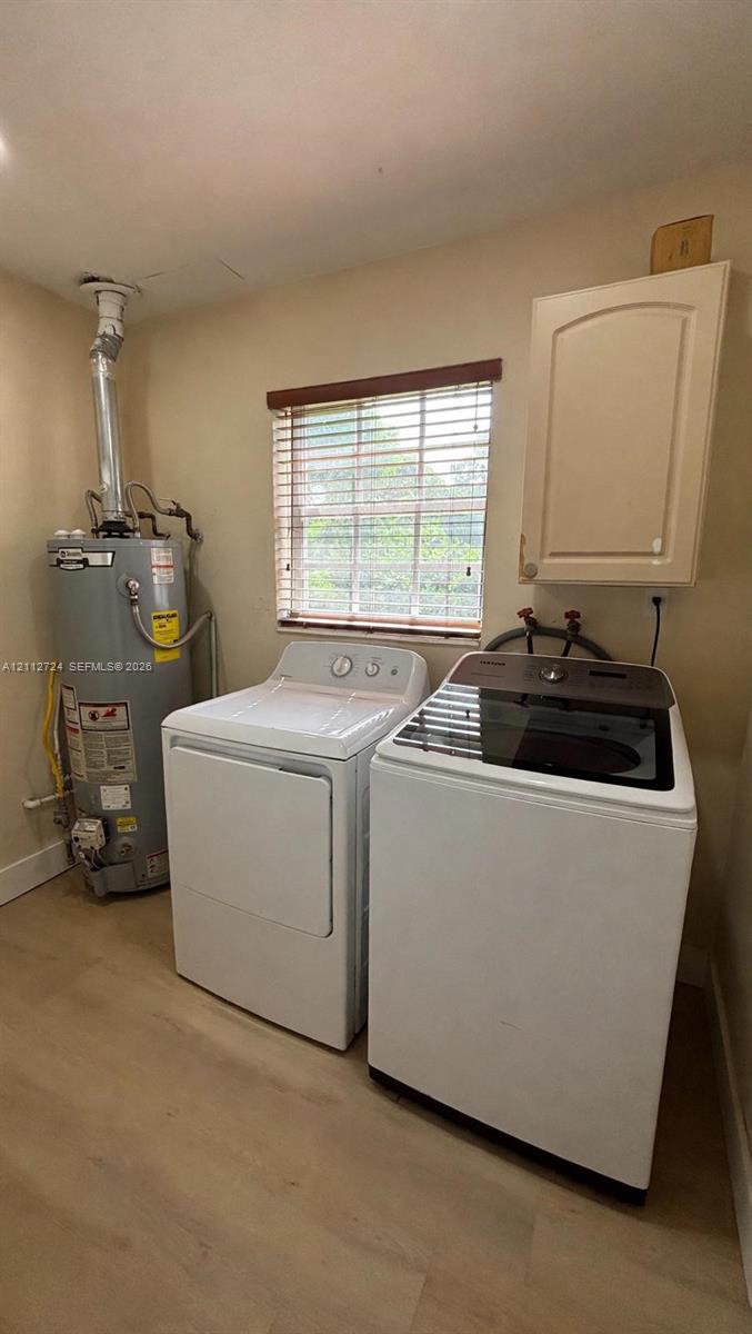 Utility area featuring wood-finish flooring, a wall-mounted cabinet, and an integrated window with horizontal blinds