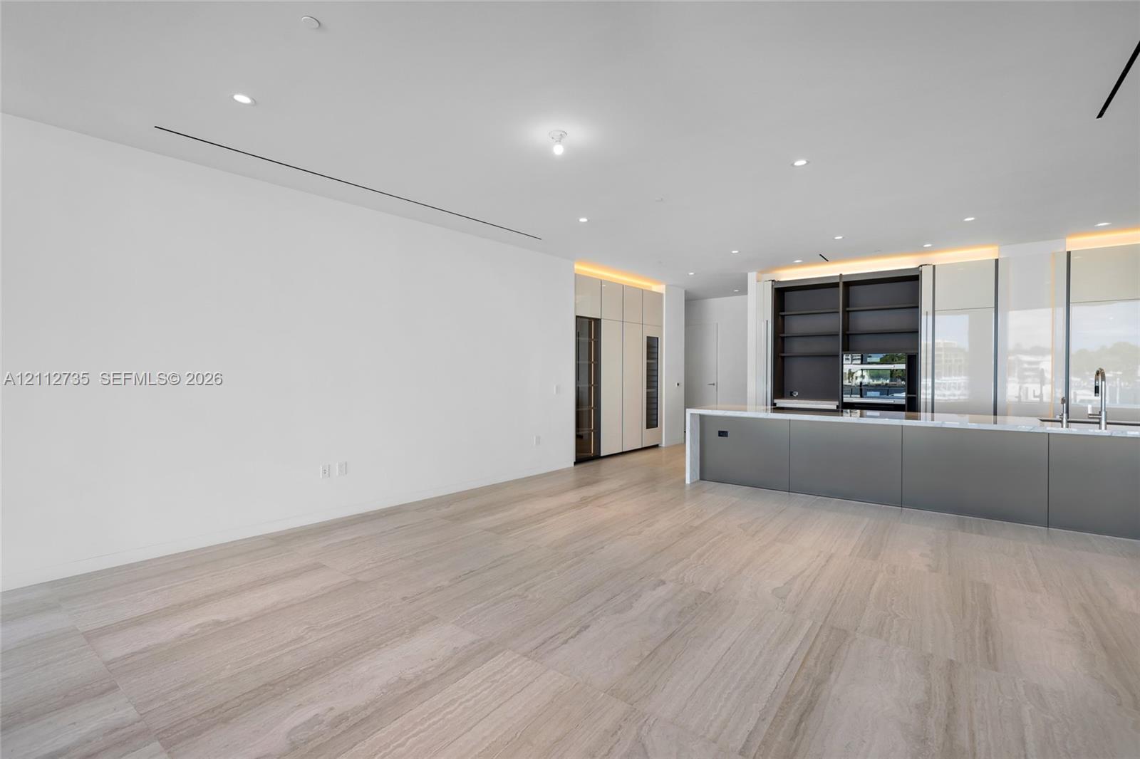 Minimalist interior featuring large-format stone-finish flooring, recessed linear lighting, and integrated ceiling spotlights