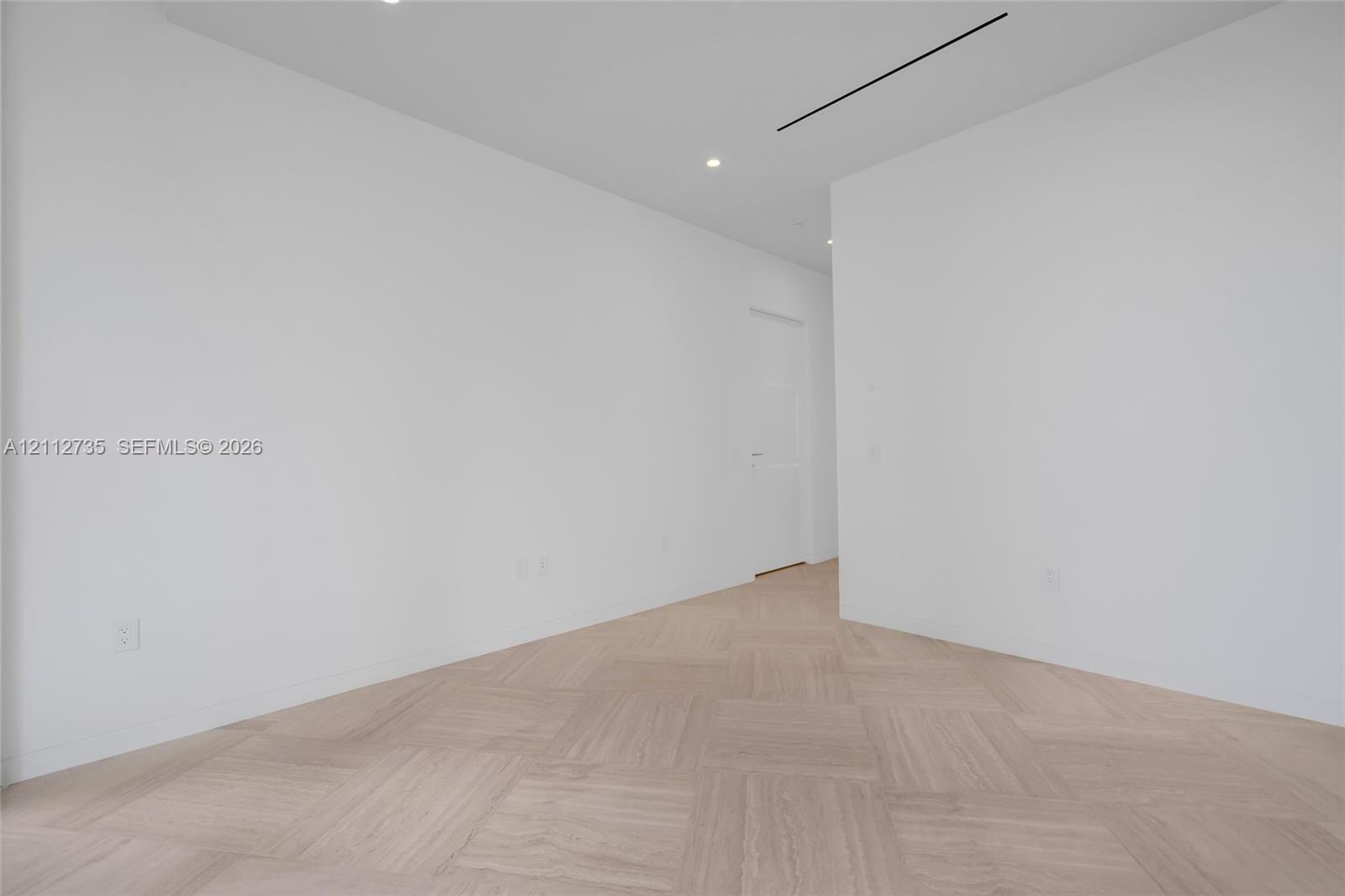 Neutral interior space featuring herringbone wood-finish flooring, recessed lighting, and crisp white wall finishes