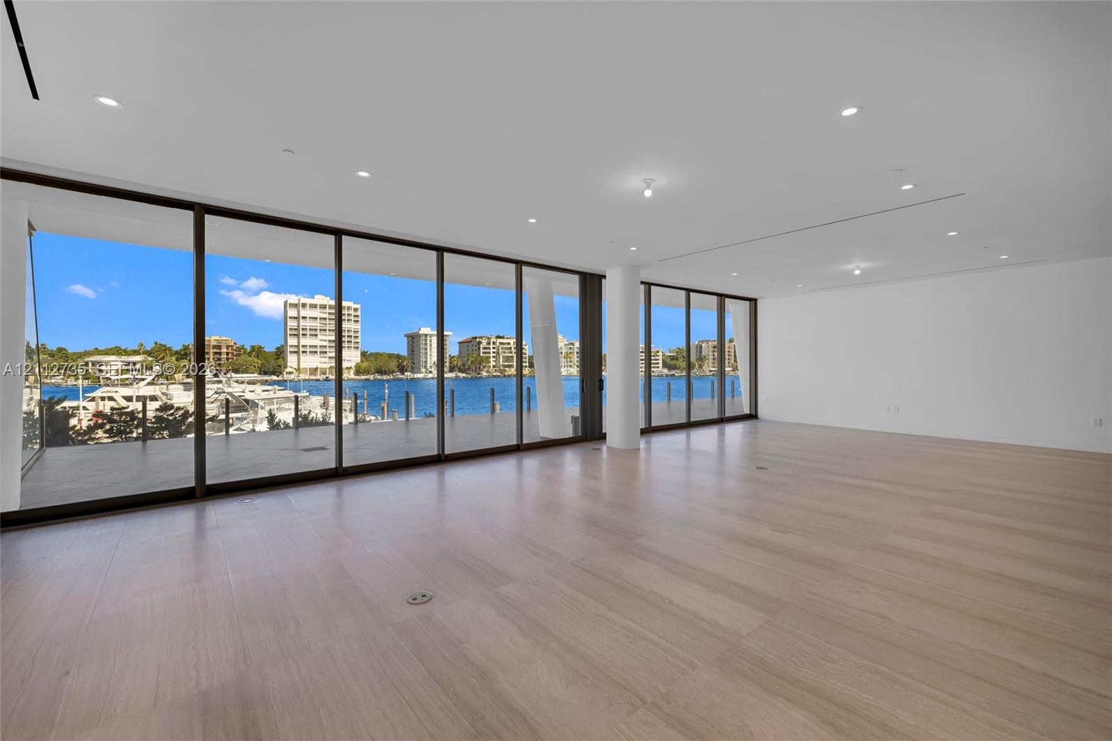 Expansive interior featuring floor-to-ceiling glass sliding doors, wood-finish flooring, recessed lighting, and a covered exterior deck Expansive interior featuring floor-to-ceiling glass sliding doors, wood-finish flooring, recessed lighting, and a covered exterior deck