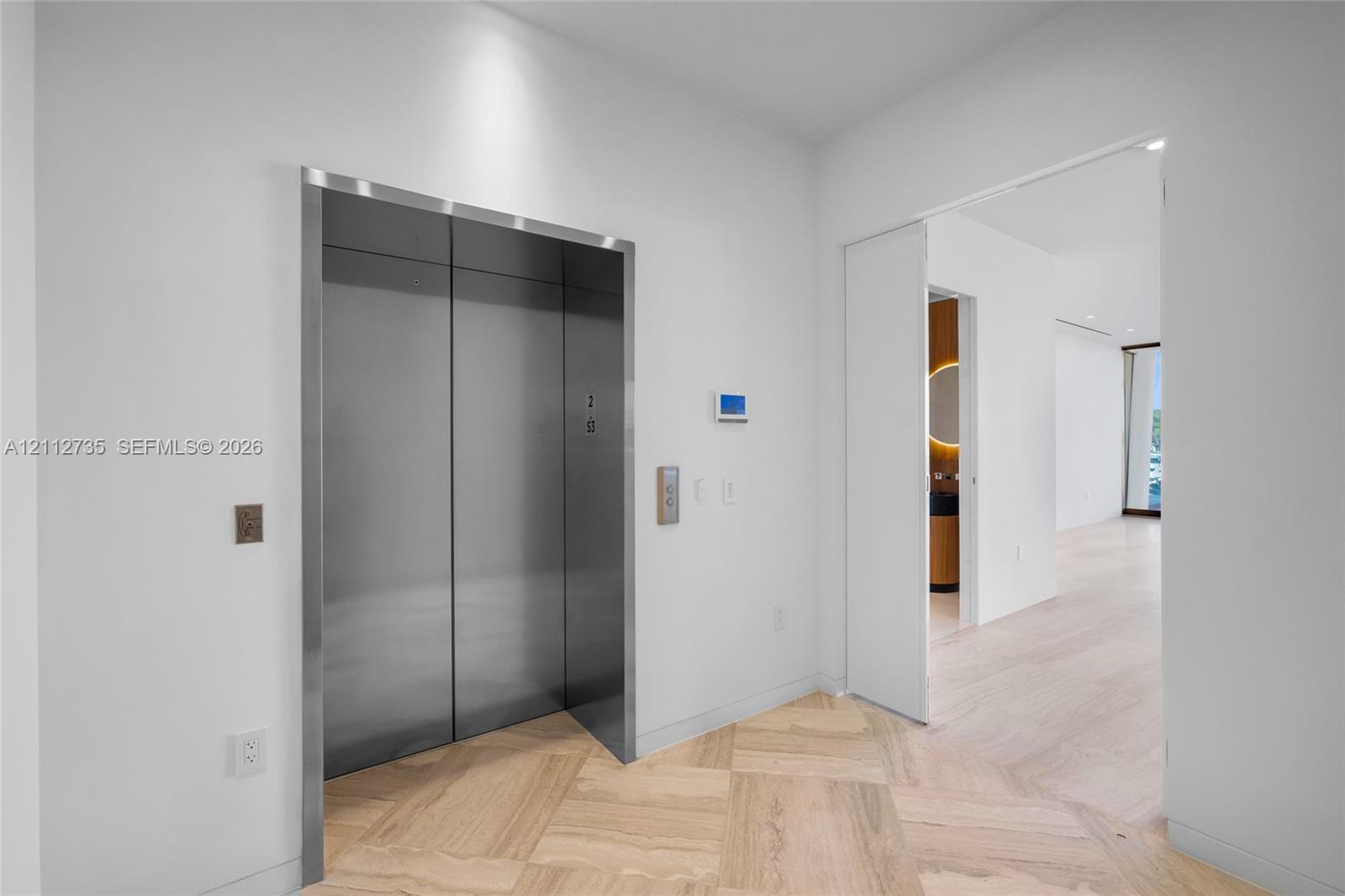 Stainless steel elevator with brushed metal finish, herringbone wood-finish flooring, and recessed ceiling lighting Stainless steel elevator with brushed metal finish, herringbone wood-finish flooring, and recessed ceiling lighting