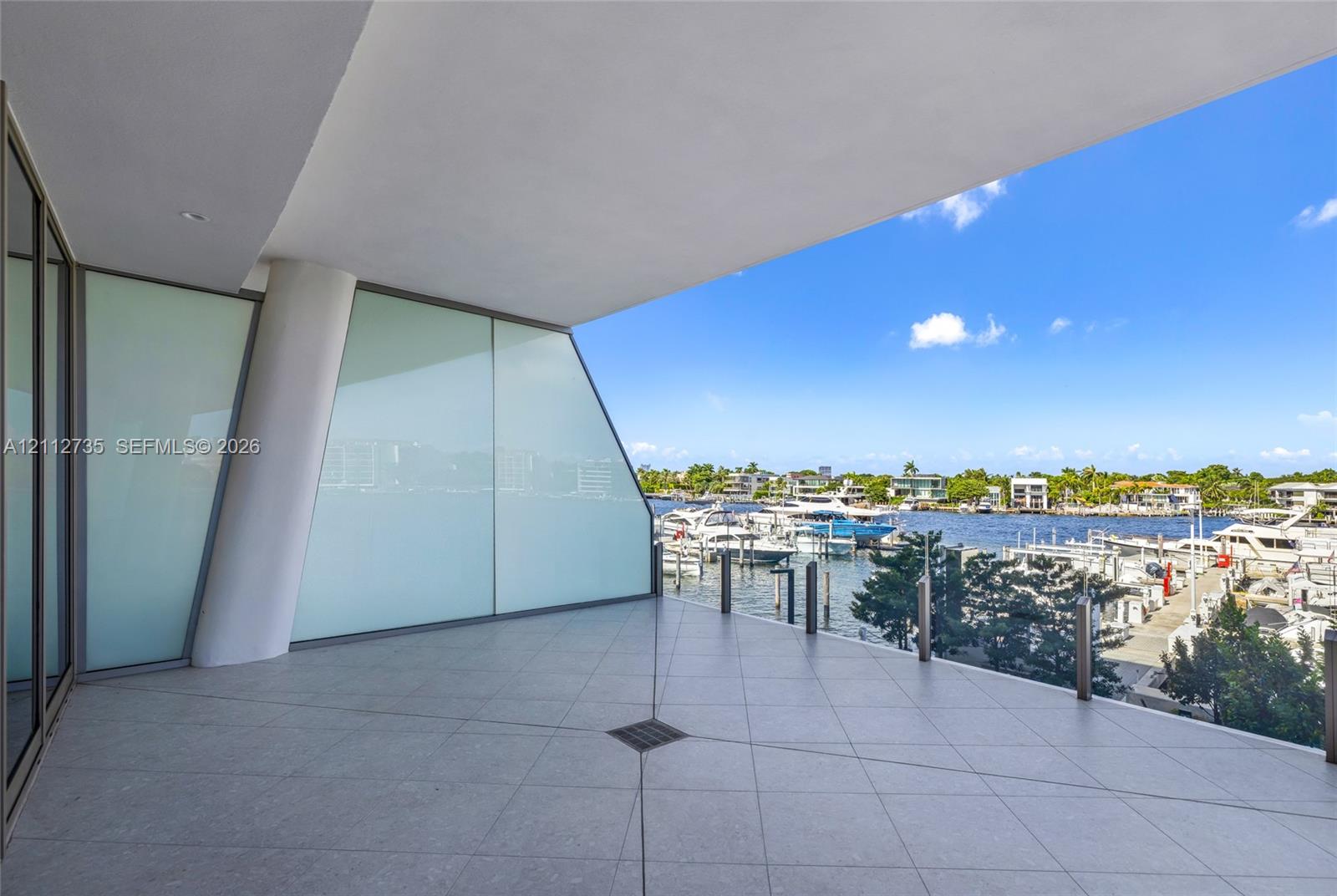 Covered balcony featuring tile flooring, structural support column, frosted glass panels, and metal railing