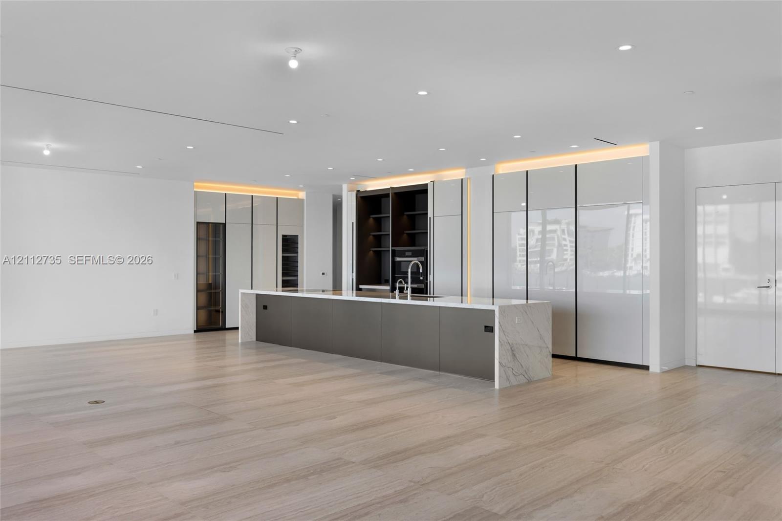Modern kitchen featuring high-gloss cabinetry, a central island with stone surfacing, integrated appliances, recessed lighting, and wood-finish flooring