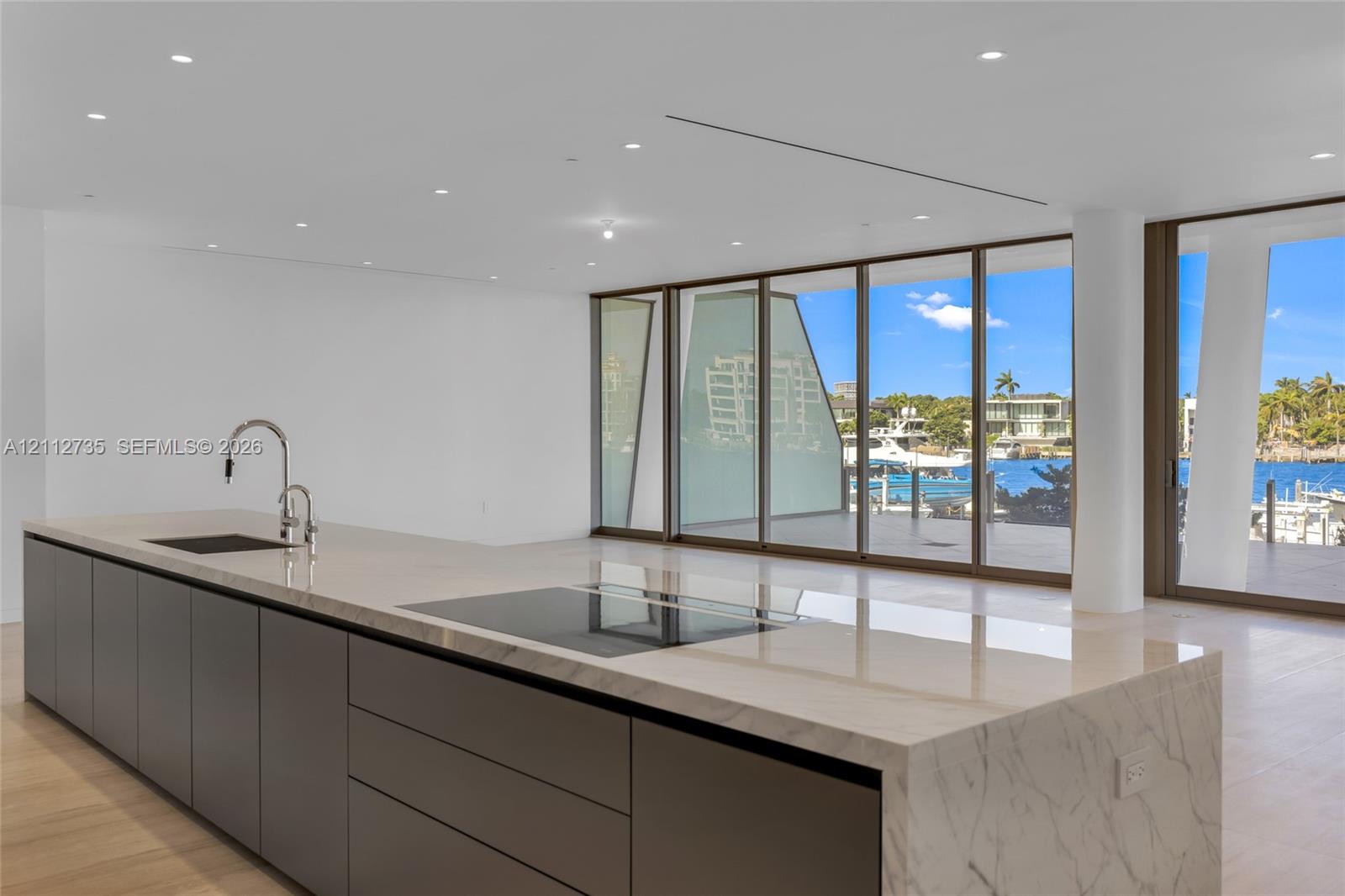 Kitchen island featuring a waterfall stone countertop, integrated cooktop, recessed lighting, floor-to-ceiling glass wall, and wood-finish flooring