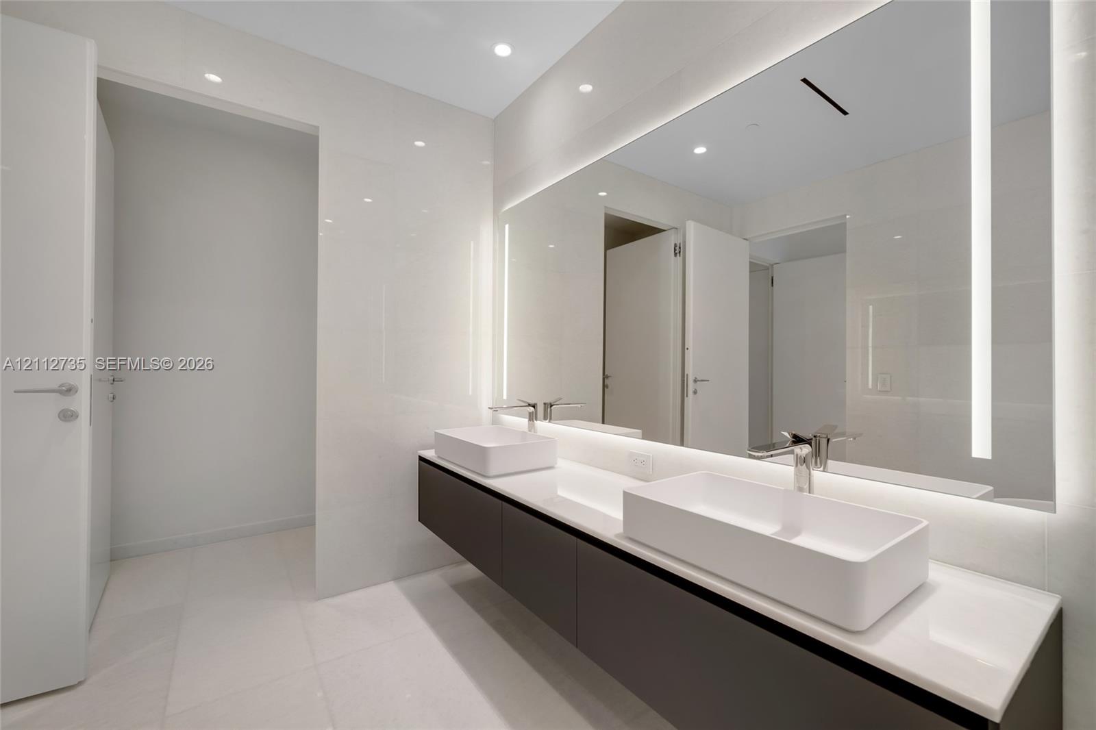 Floating dual-sink vanity featuring square vessel basins, quartz countertop, large wall-to-wall integrated LED vanity mirror, and polished chrome fixtures