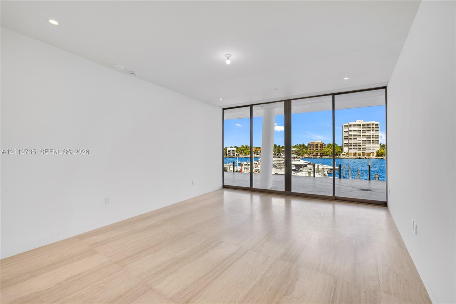 Floor-to-ceiling glass sliding doors, wood-finish flooring, recessed lighting, and water frontage