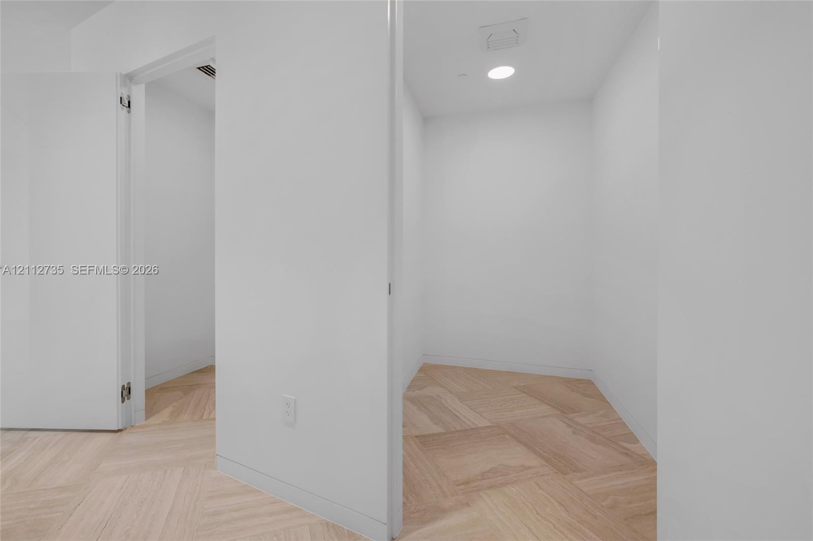 Neutral-toned interior space featuring chevron-pattern wood-finish flooring and recessed lighting