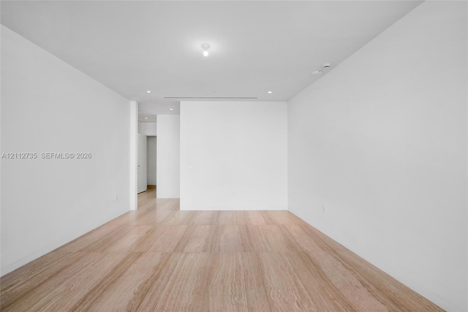 Interior space featuring light wood-finish flooring, smooth white walls, recessed ceiling lighting, and a linear slot ceiling diffuser