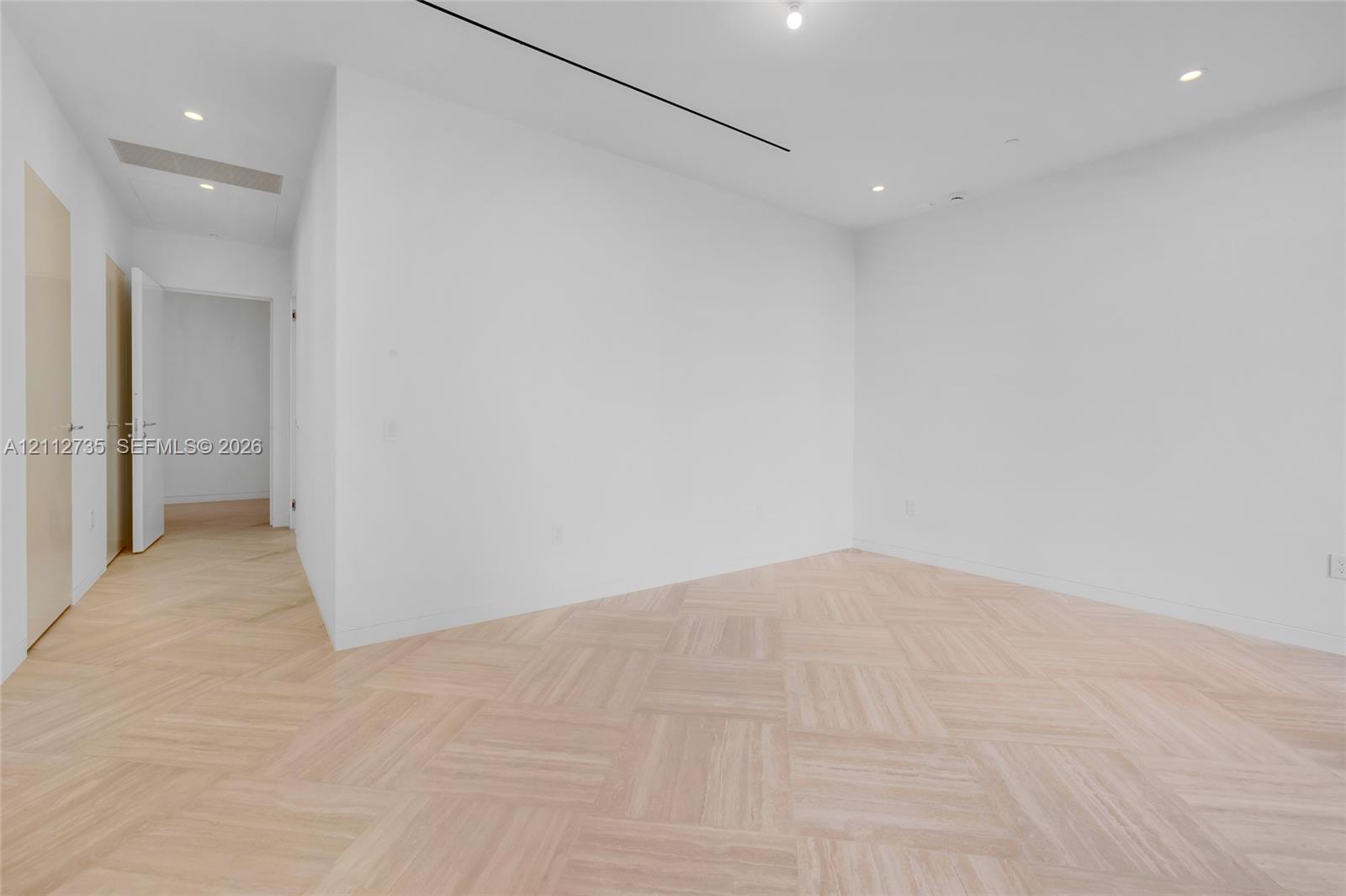 Interior space featuring light-toned wood-finish flooring in a herringbone pattern, recessed lighting, and smooth-finish white walls