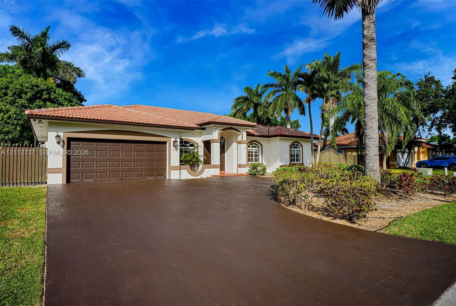 Single-story residence featuring a tile roof, stucco exterior, two-car garage, and a paved driveway Single-story residence featuring a tile roof, stucco exterior, two-car garage, and a paved driveway