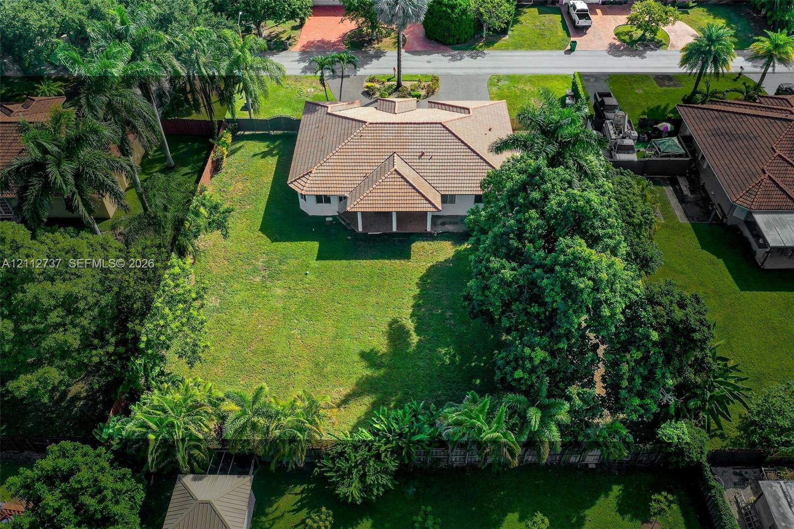 Expansive lot featuring a multi-gabled tile roof, a rear covered patio, mature landscaping, and an extensive lawn area Expansive lot featuring a multi-gabled tile roof, a rear covered patio, mature landscaping, and an extensive lawn area