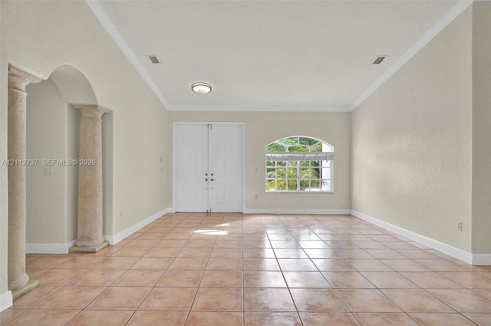 Vaulted ceilings, arched entry with dual stone-finish pillars, ceramic tile flooring, double front entry doors, and an arched window