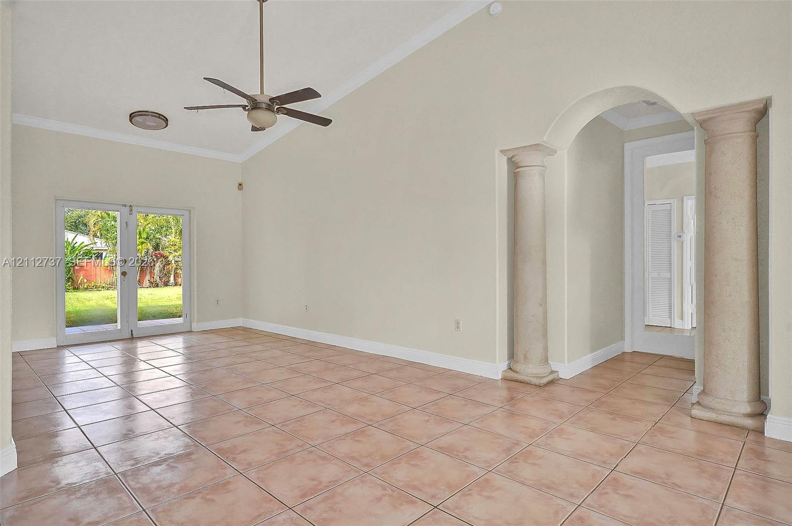 Vaulted ceilings, large-format tile flooring, double-door glass entry to the exterior, and decorative architectural columns framing the entryway