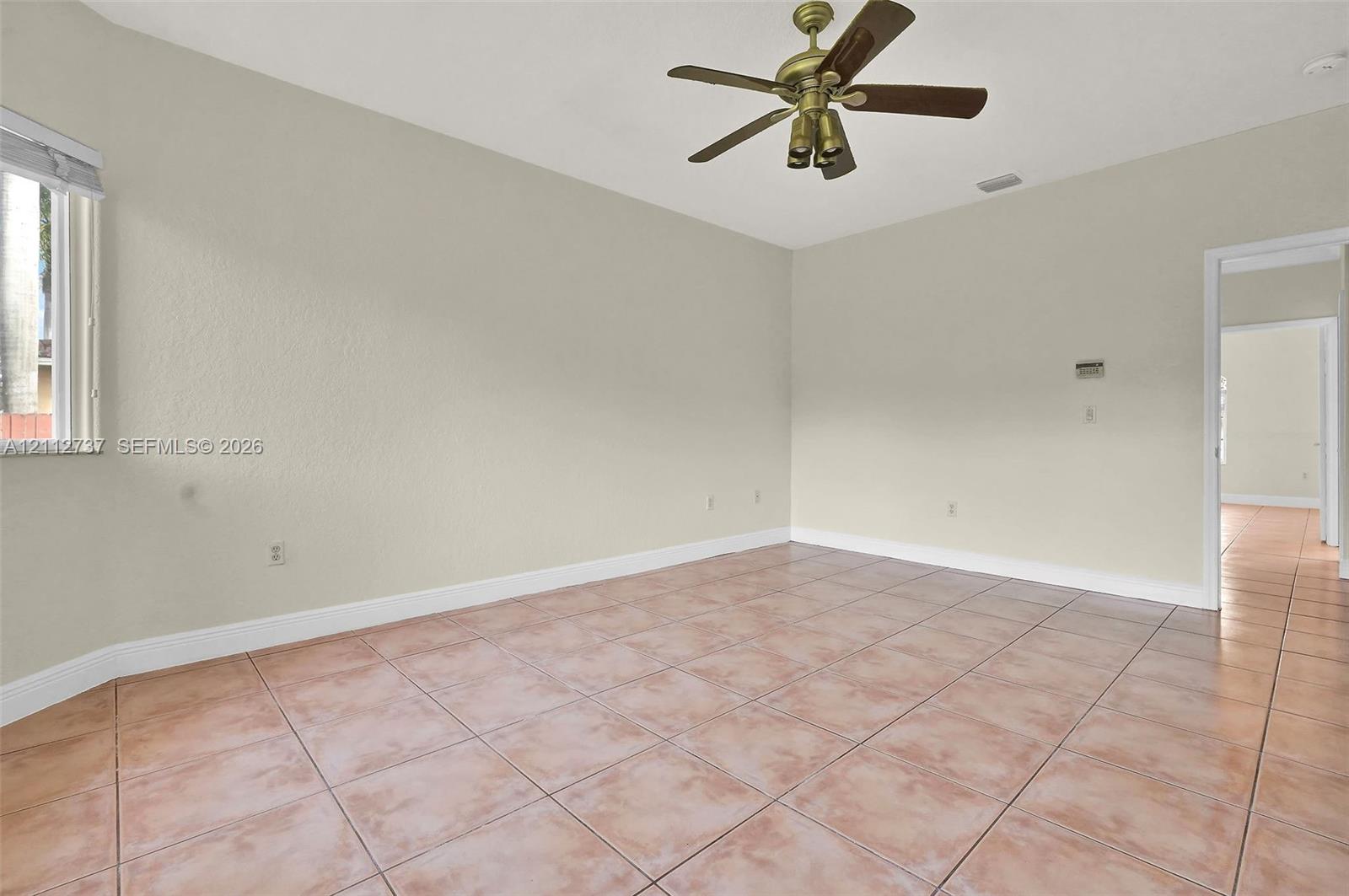 Neutral-toned interior featuring ceramic tile flooring, a multi-blade ceiling fan with integrated lighting, and a single-hung window