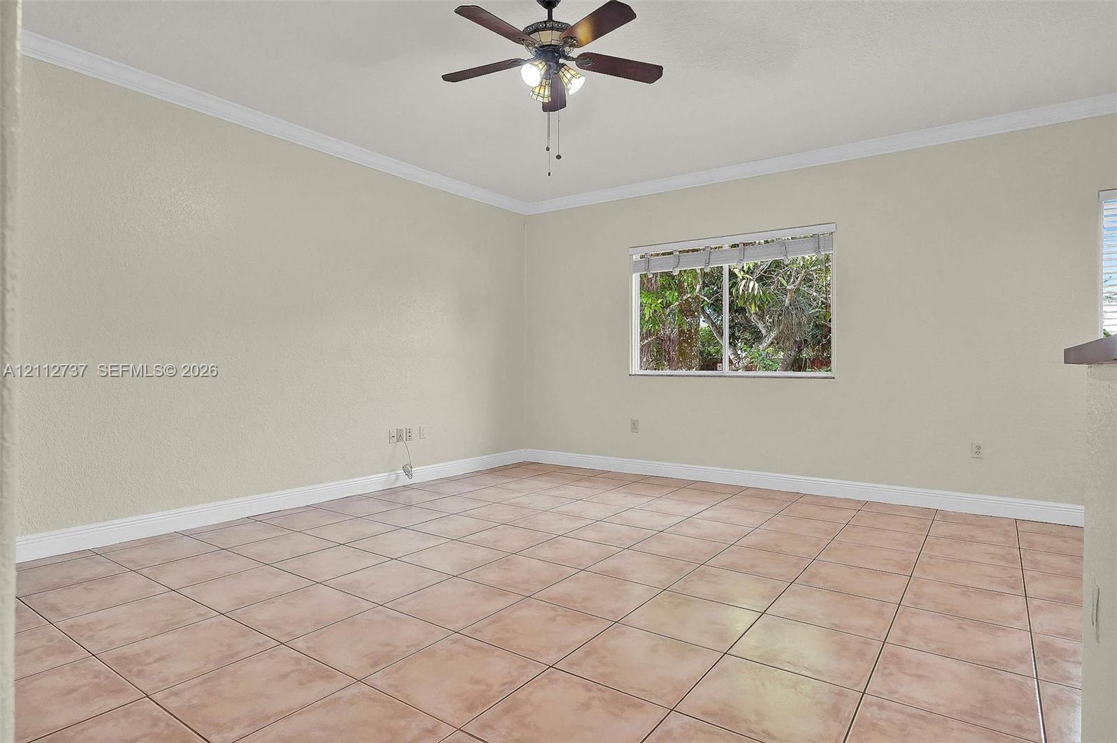 Neutral-toned interior featuring ceramic tile flooring, crown molding, and a multi-light ceiling fan