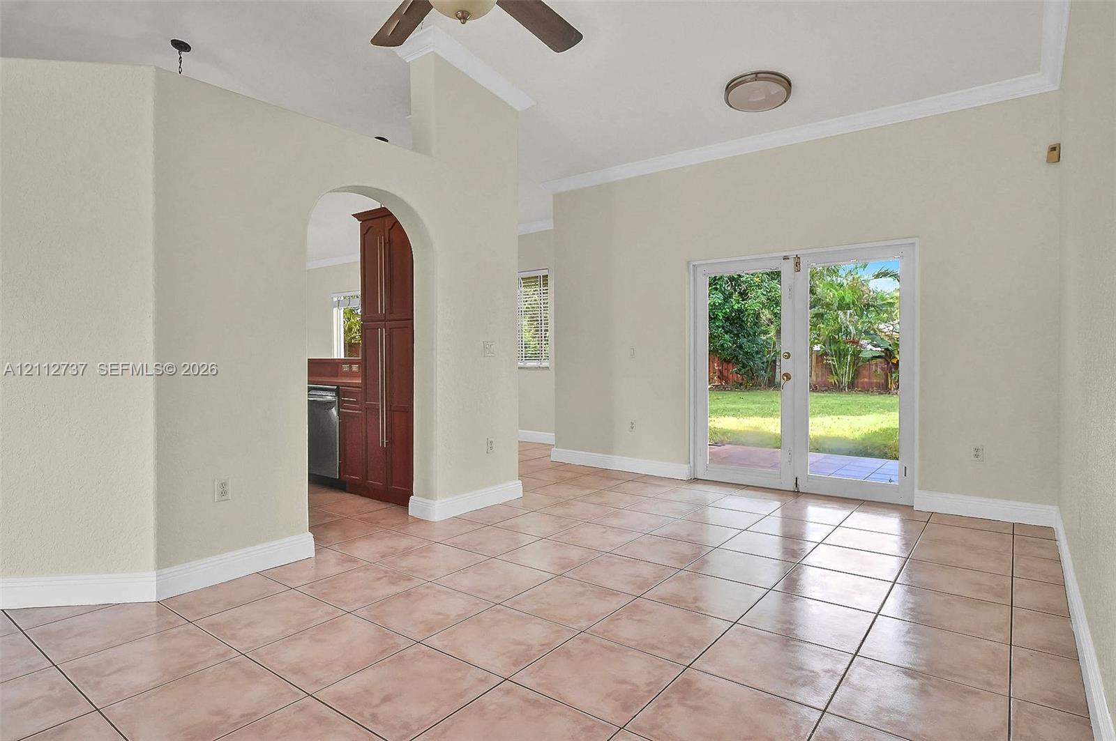 Interior space featuring large-format ceramic tile flooring, arched architectural detailing, and dual glass paneled doors providing exterior access