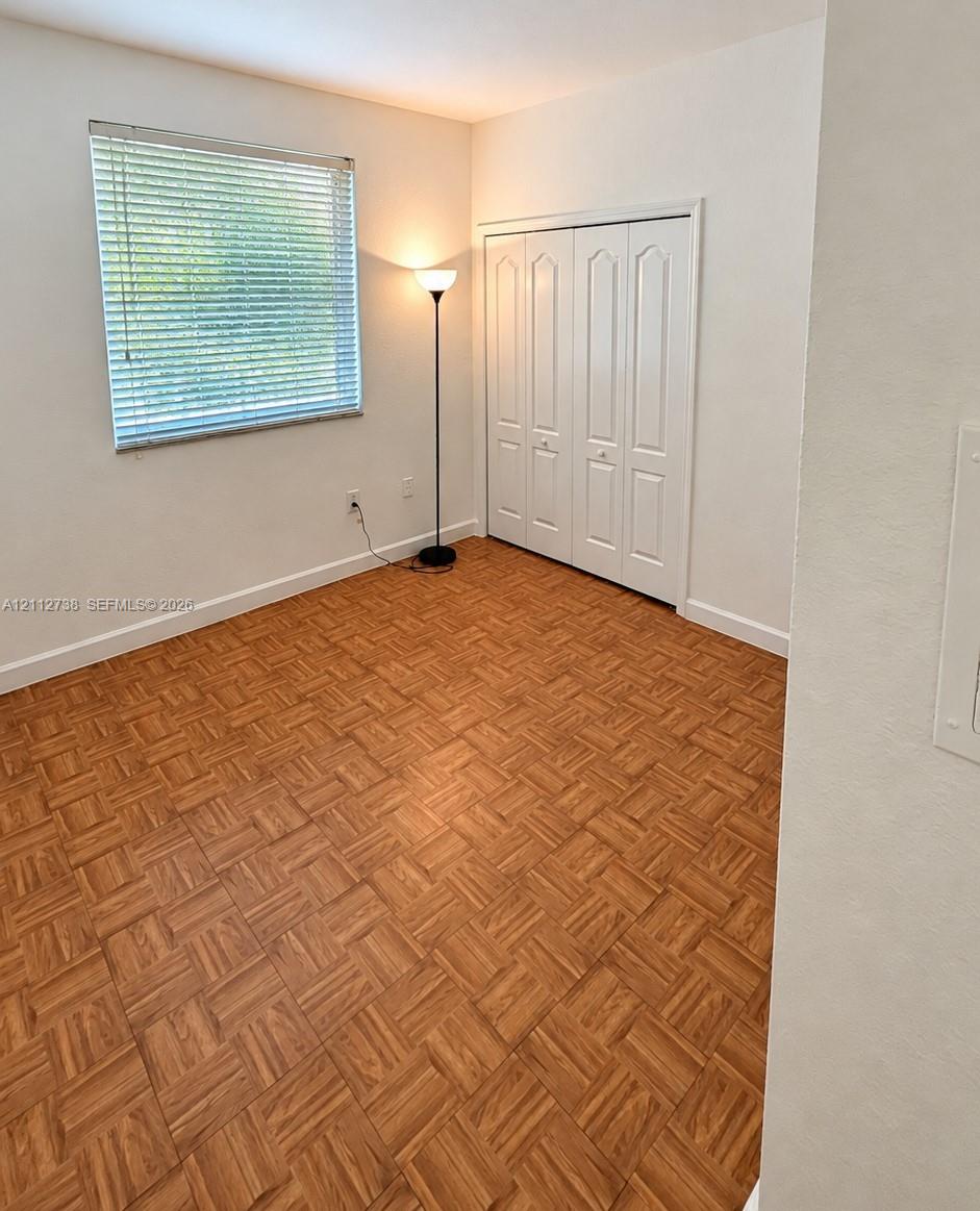 Parquet wood-finish flooring, white bi-fold closet doors, and single-pane window with horizontal blinds