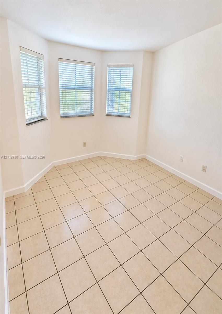 Interior room featuring large format tile flooring and a tripartite bay window configuration with integrated blinds Interior room featuring large format tile flooring and a tripartite bay window configuration with integrated blinds