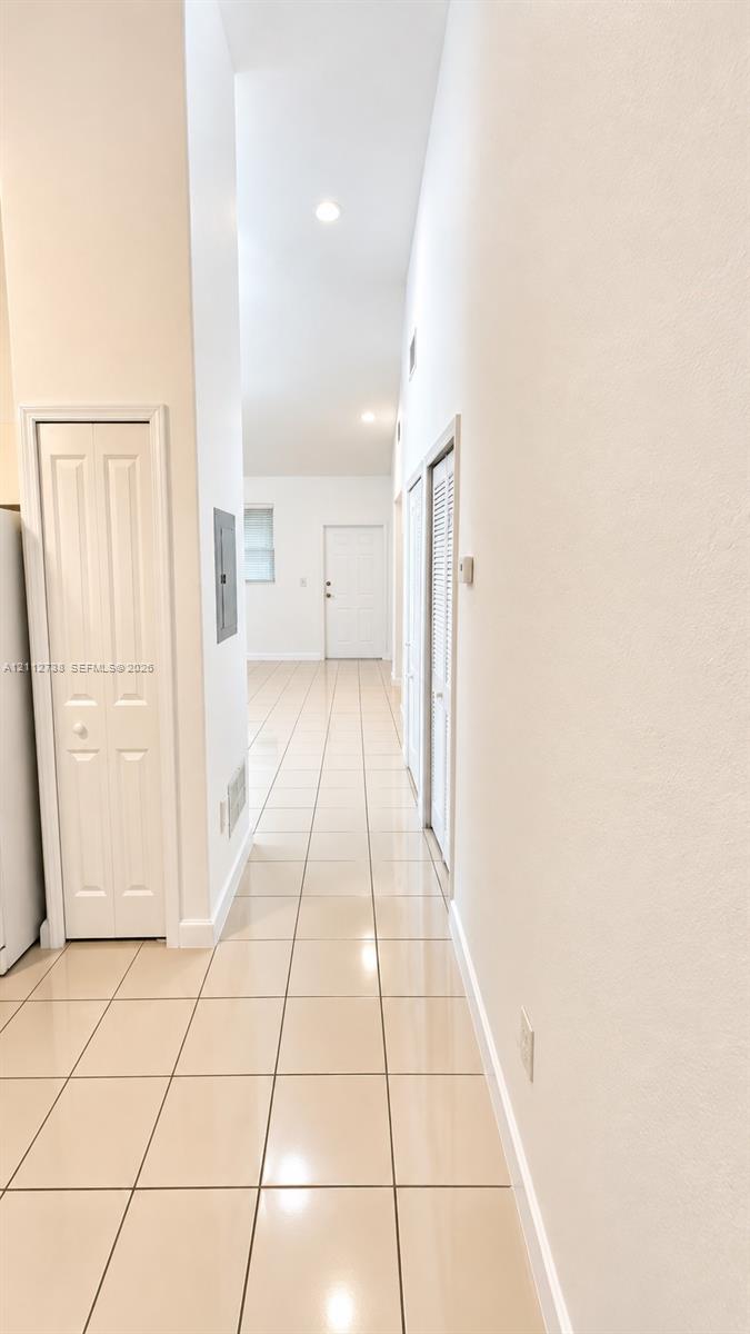High-ceiling interior featuring neutral ceramic tile flooring, recessed lighting, and white paneled interior doors High-ceiling interior featuring neutral ceramic tile flooring, recessed lighting, and white paneled interior doors