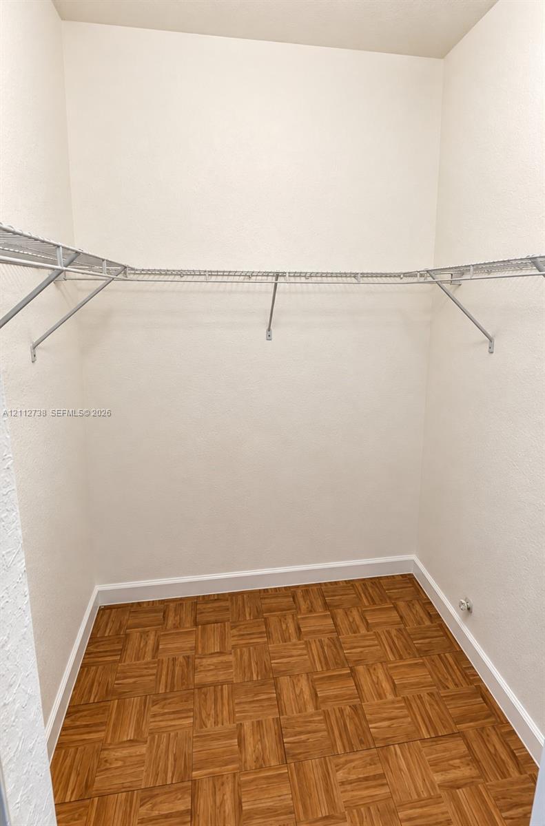 Storage space featuring parquet wood-finish flooring and wall-mounted metal wire shelving