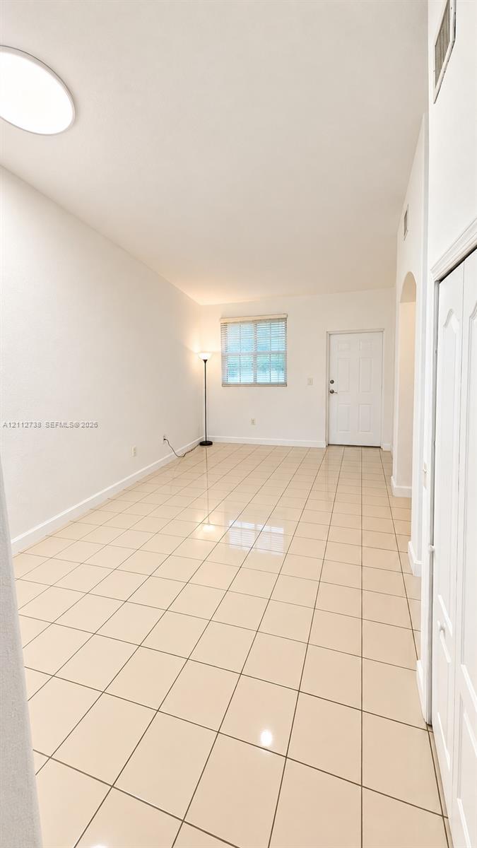 High-ceiling room featuring large-format tile flooring, recessed lighting, and a six-panel entry door High-ceiling room featuring large-format tile flooring, recessed lighting, and a six-panel entry door