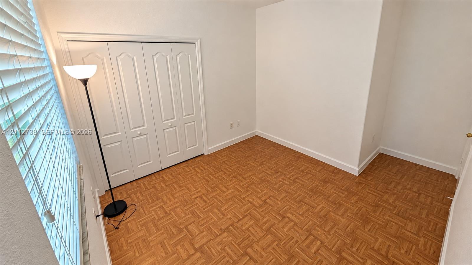 Room featuring parquet wood-finish flooring, white walls, and a four-panel bi-fold closet