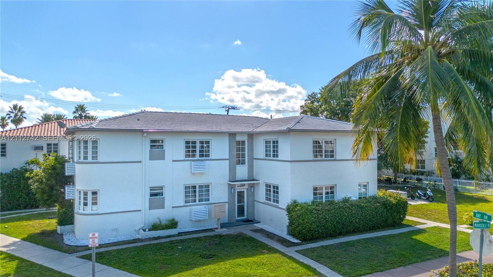 Two-story stucco exterior featuring a hipped tile roof, multi-pane windows, and corner architectural detailing